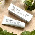 Rejuveon PDRN cream tube and box on a wooden surface with green leaves.